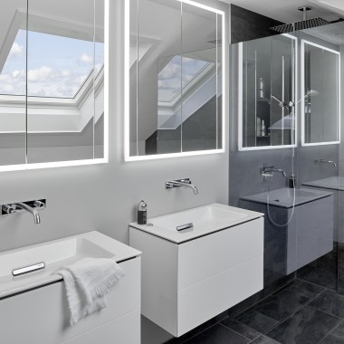 Badkamer onder een schuin dak met twee wastafels en spiegels