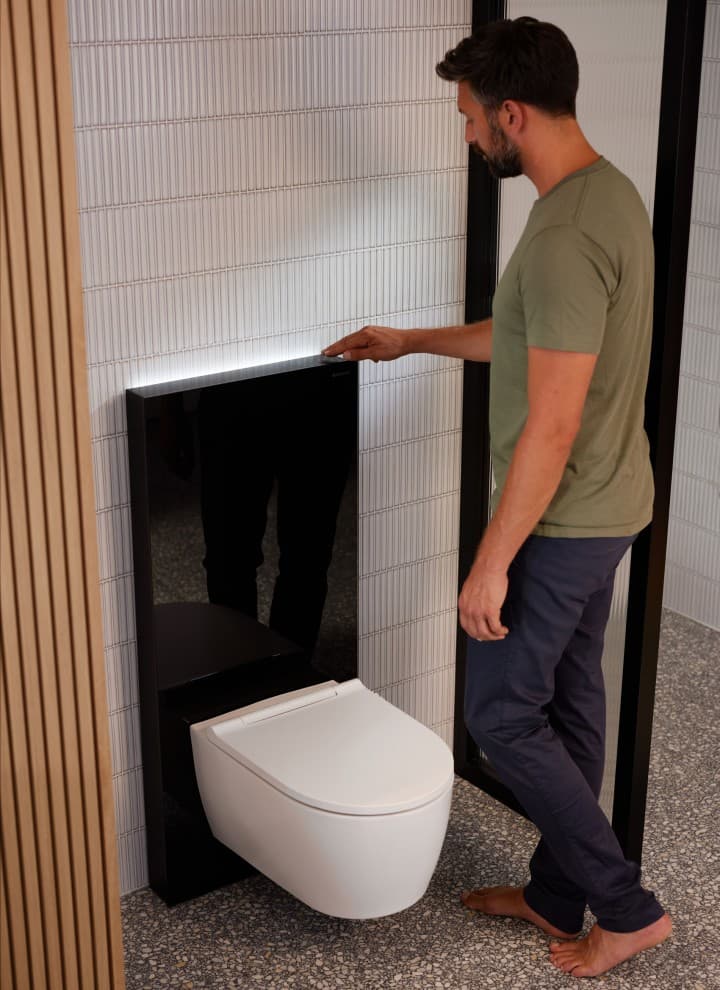 Man naast Geberit Monolith Plus met ComfortLight Man naast Geberit Monolith Plus met ComfortLight