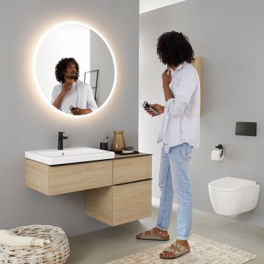 Man bekijkt zichzelf in een Geberit Option Round lichtspiegel Man bekijkt zichzelf in een Geberit Option Round lichtspiegel