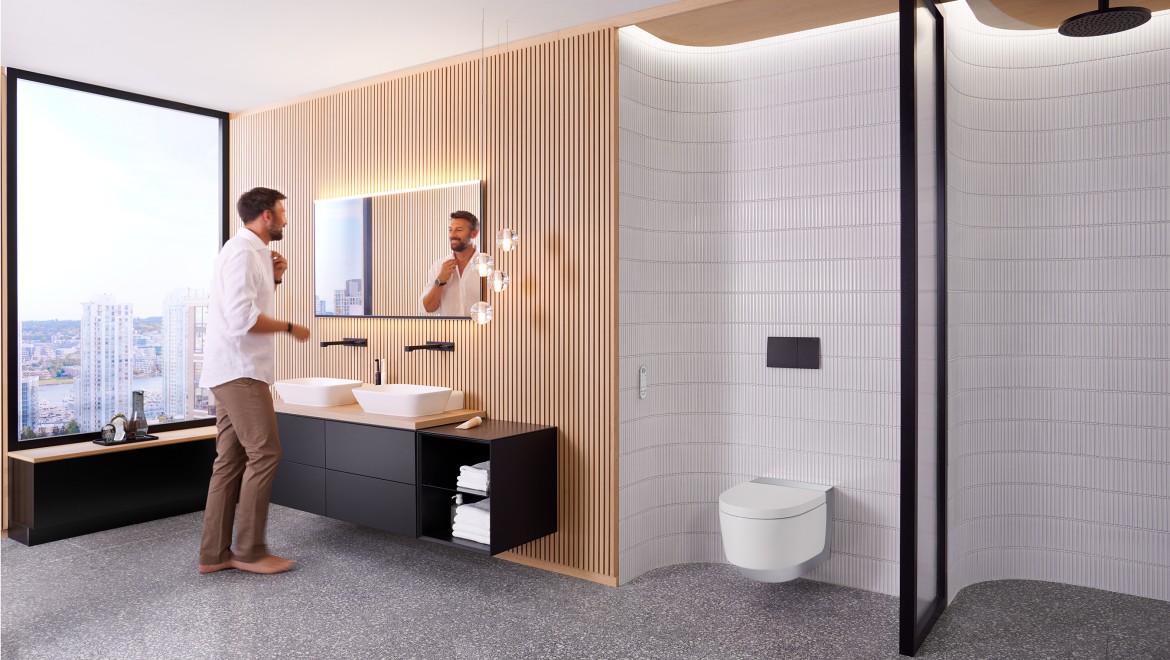 Man in badkamer voor spiegel Geberit Option Plus Square en zwart Geberit ONE badkamermeubel (© Geberit)