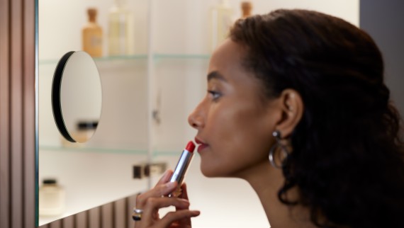 Vrouw brengt lippenstift aan voor vergrootspiegel (© Geberit)
