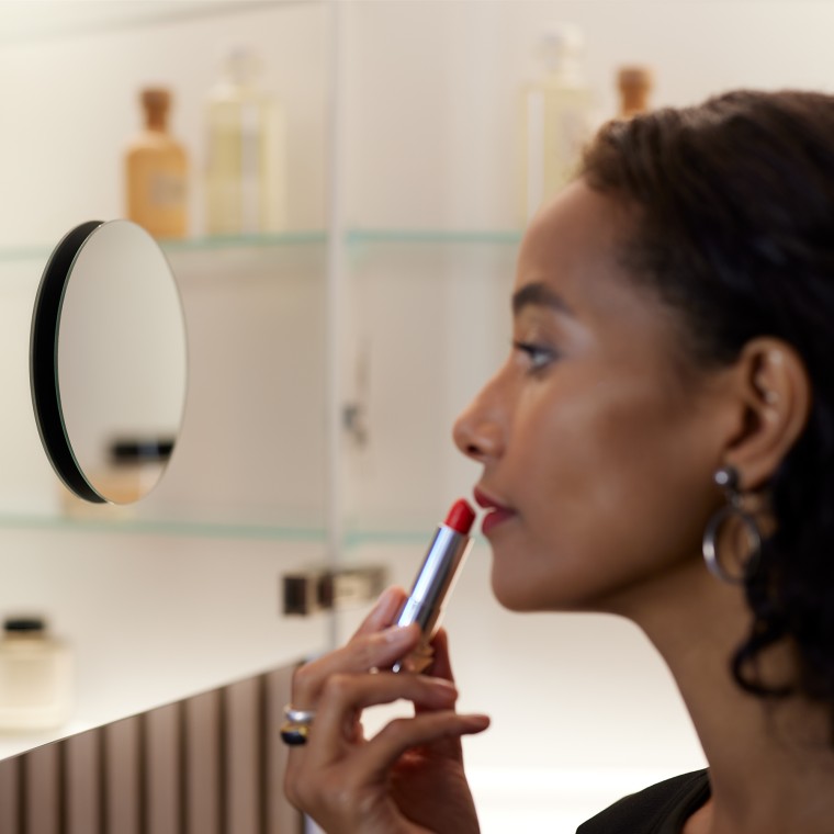 Vrouw die make-up aanbrengt voor de spiegel