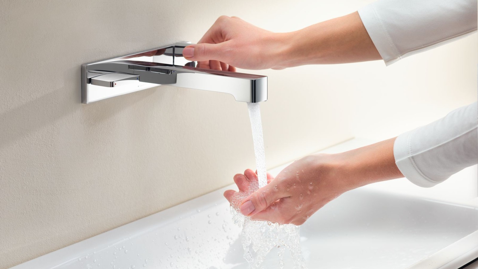 Handen die een Geberit ONE-kraan draaien en de watertoevoer en temperatuur controleren Handen die een Geberit ONE-kraan draaien en de watertoevoer en temperatuur controleren