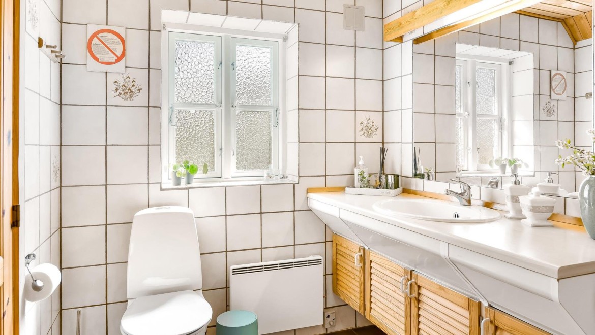 De originele badkamer met vloerstaande wc, witte tegels en houten badkamermeubels (© @triner2 en @strandparken3)