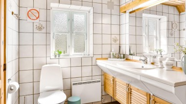De originele badkamer met vloerstaande wc, witte tegels en houten badkamermeubels (© @triner2 und @strandparken3)