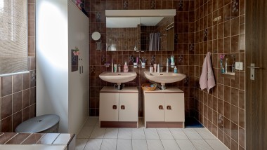 Badkamer met bruine tegels en twee wastafels