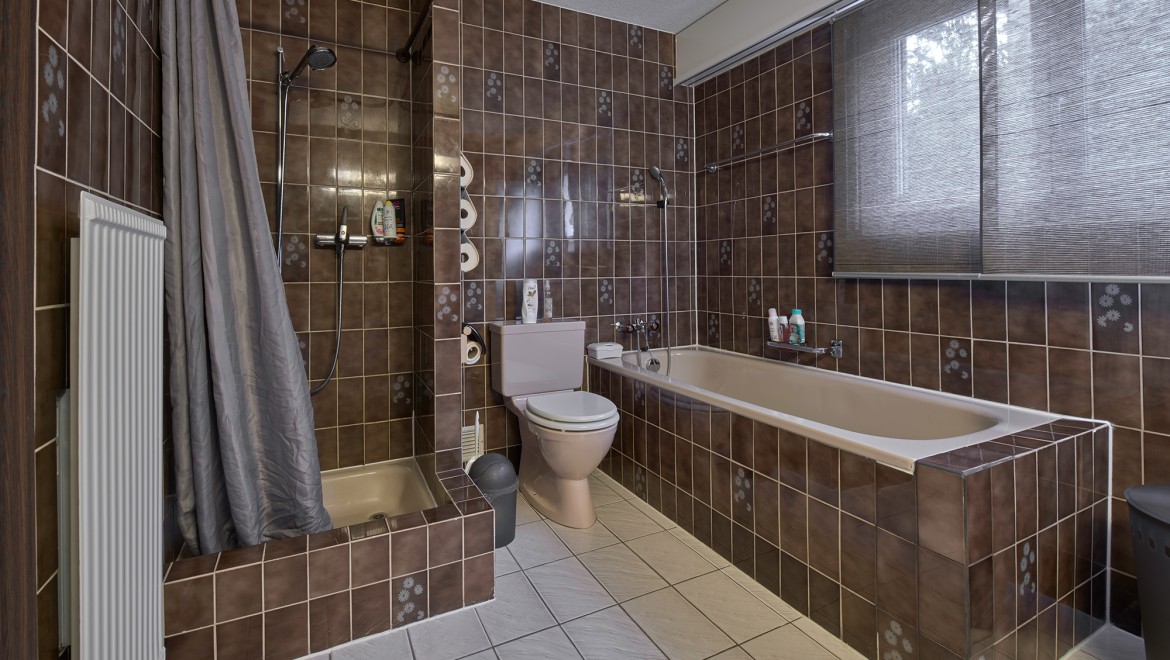 Badkamer met smalle doucheruimte, bad en vloerstaande wc