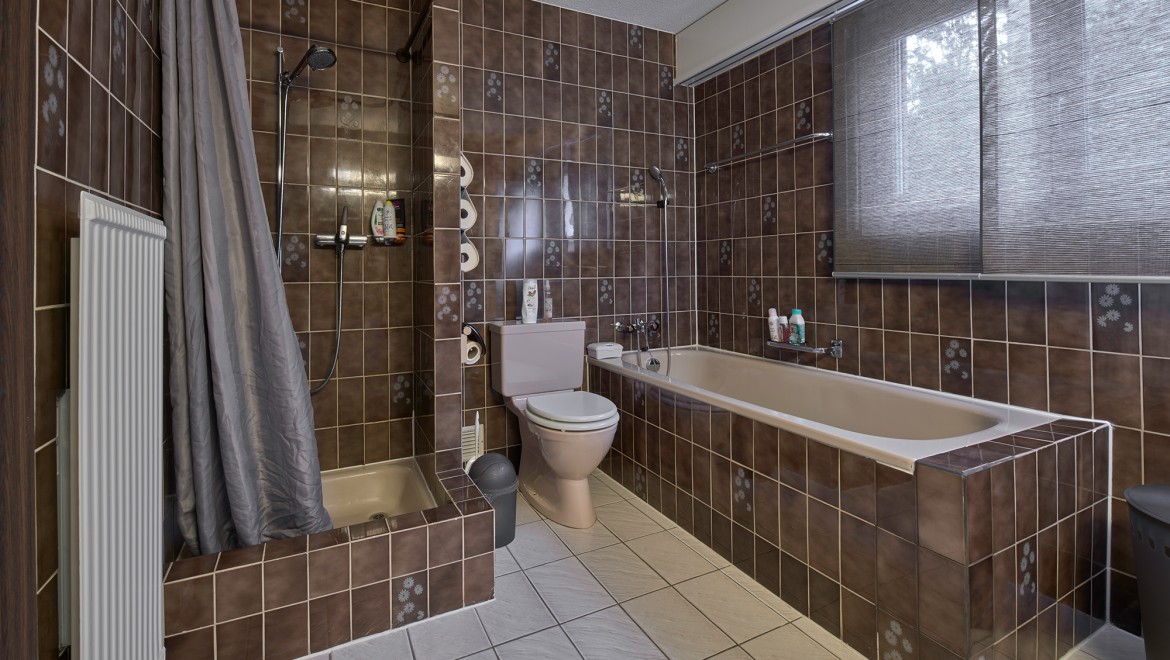 Badkamer met smalle doucheruimte, bad en vloerstaande wc Badkamer met smalle doucheruimte, bad en vloerstaande wc