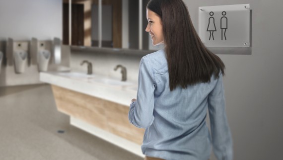 Donkerharige jonge vrouw in een openbaar toilet Donkerharige jonge vrouw in een openbaar toilet