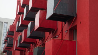 Een opvallende rode gevel met vooraan kubusvormige balkons is de nieuwe blikvanger aan de Goldsteinstrasse in Frankfurt am Main (DE) (© Geberit)