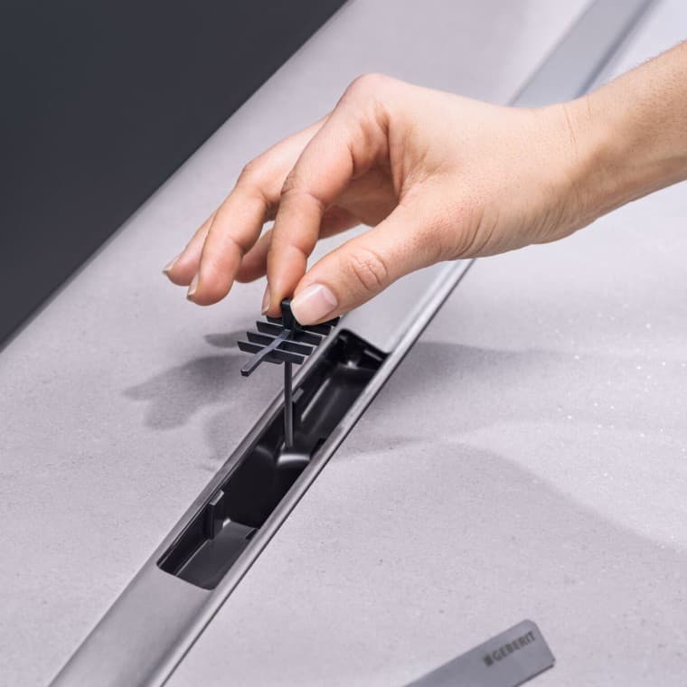 Met de hand een kamvormige haarzeef in de afvoer plaatsen Met de hand een kamvormige haarzeef in de afvoer plaatsen