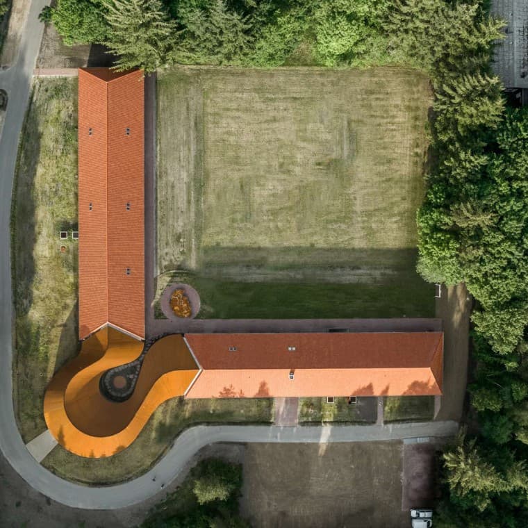 Het bovenaanzicht toont het ronde nieuwe gebouw dat de twee historische gebouwen met de pannendaken verbindt (© R_Hjortshoj) Het bovenaanzicht toont het ronde nieuwe gebouw dat de twee historische gebouwen met de pannendaken verbindt (© R_Hjortshoj)